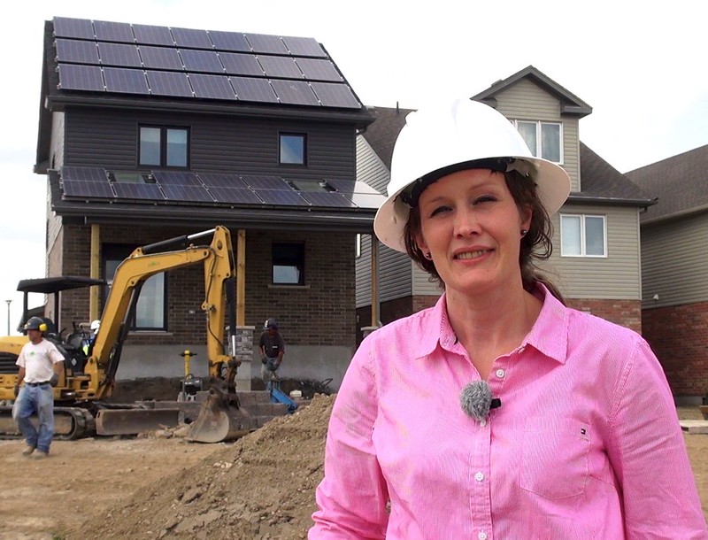 A woman construction worker in front of a a house