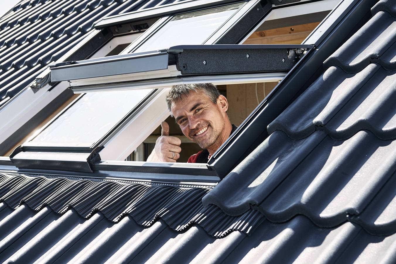 A man giving a thumbs up from a Velux roof window