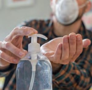 workman sanitising his hands and wearing a mask