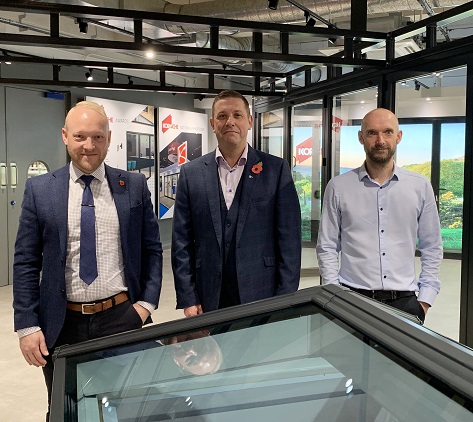 Three men standing in a factory foyer