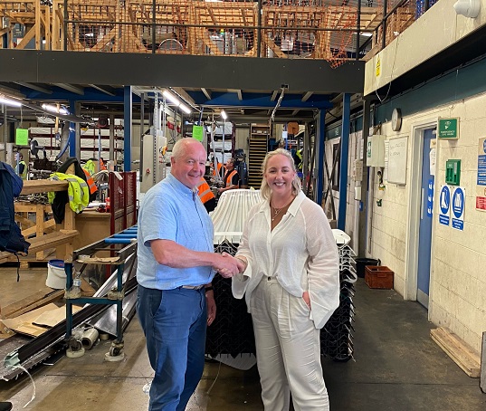 Two people posing for a picture in a factory