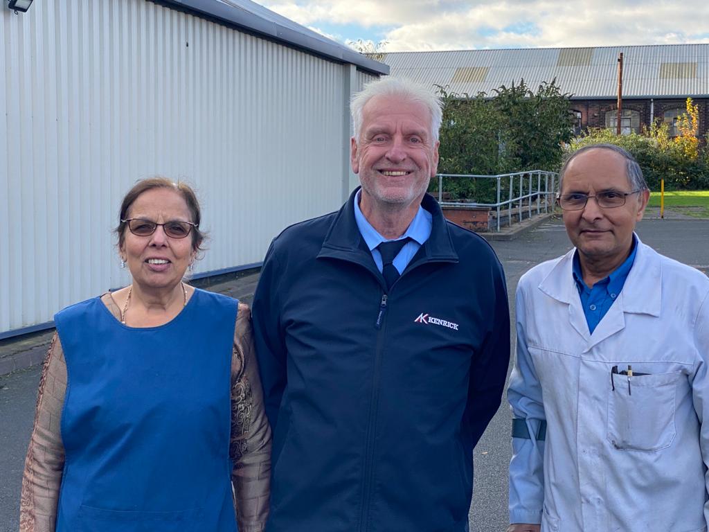 Three people outside a factory