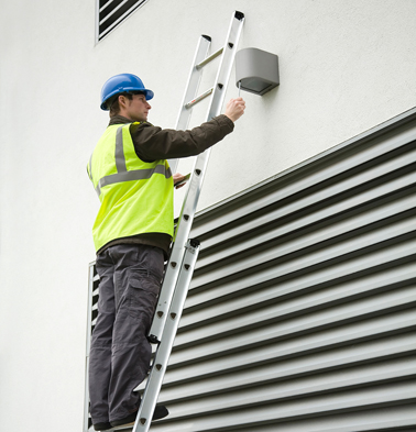 A man on a ladder fixing a light working at height