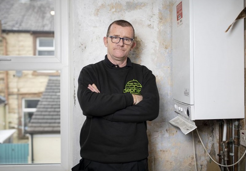 A plumber next to a gas boiler