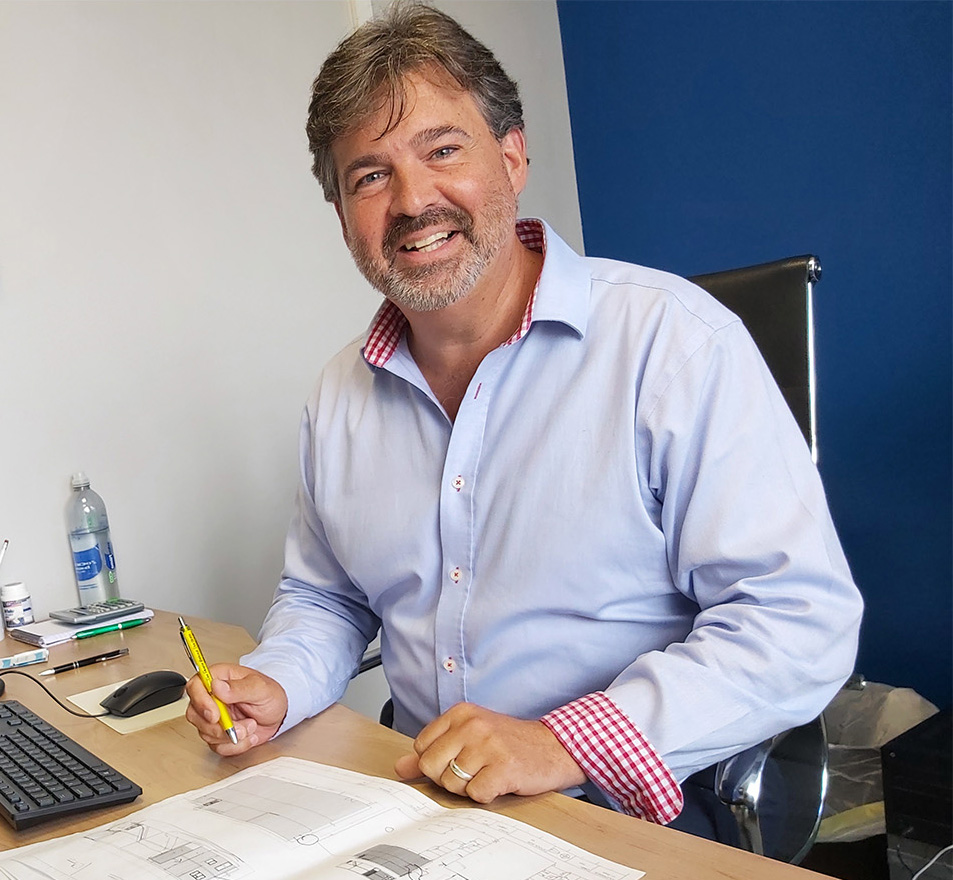 A smiling man with a beard at his desk