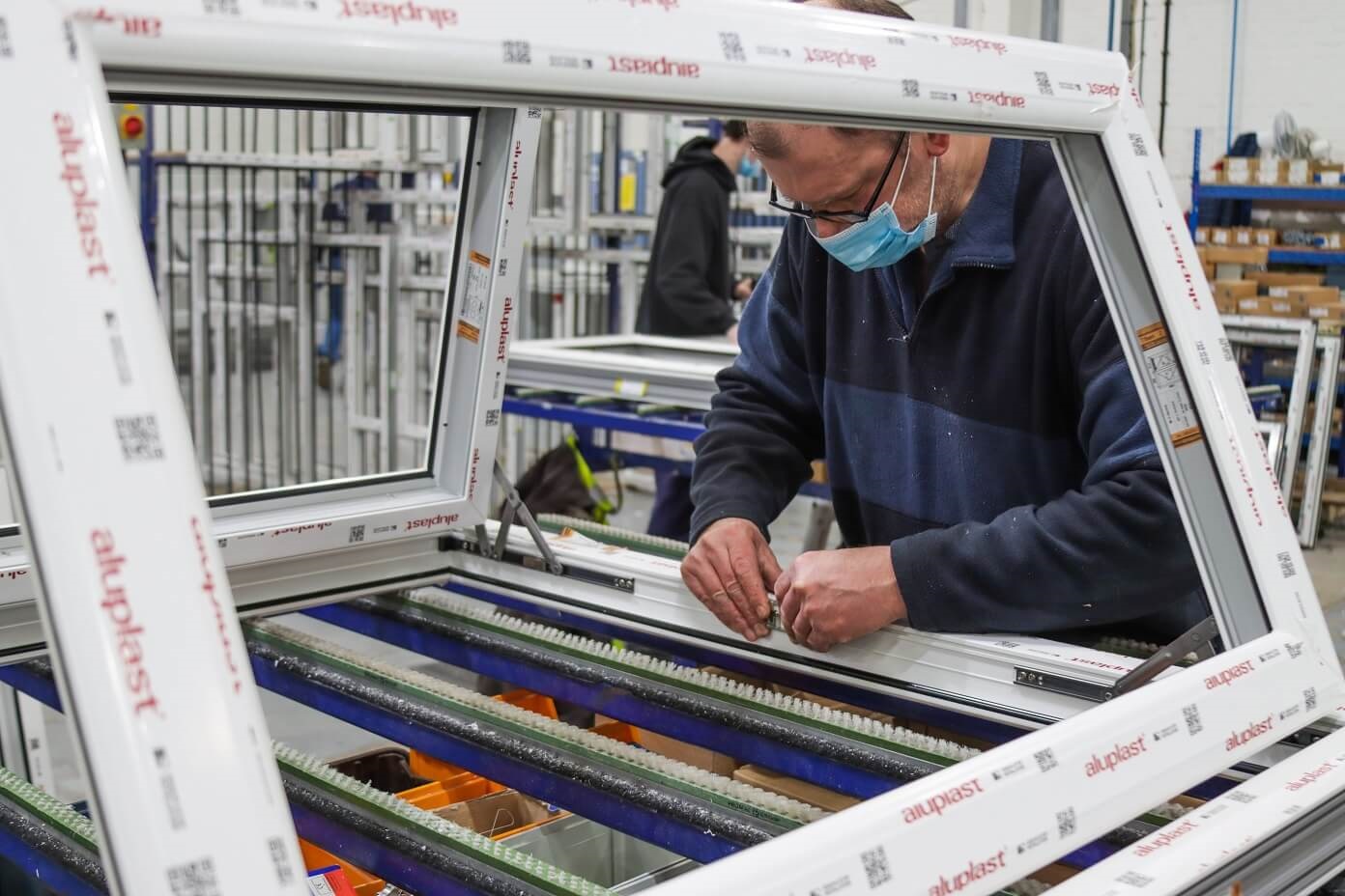 A man assembling a PVC-U window in a factory