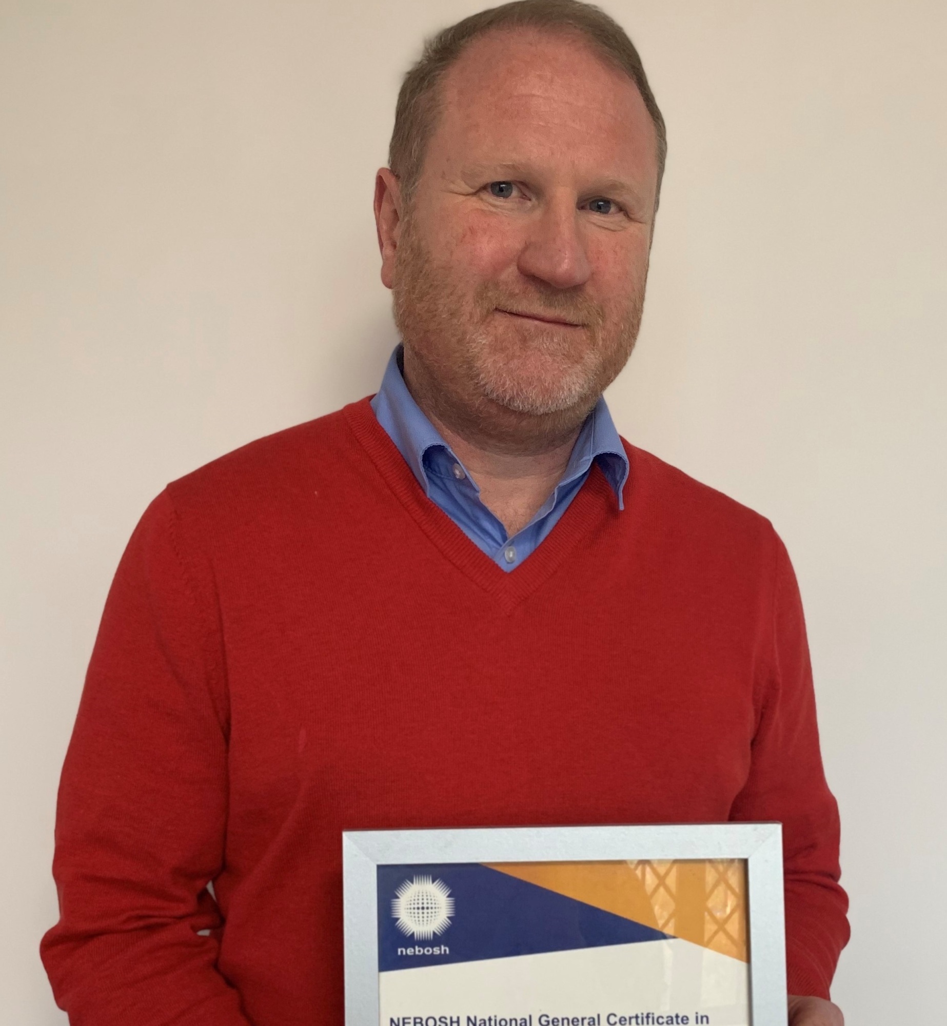 A man standing holding a certificate