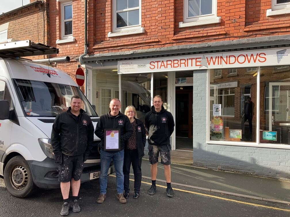 People standing outside Starbrite Windows' shop holding a certificate