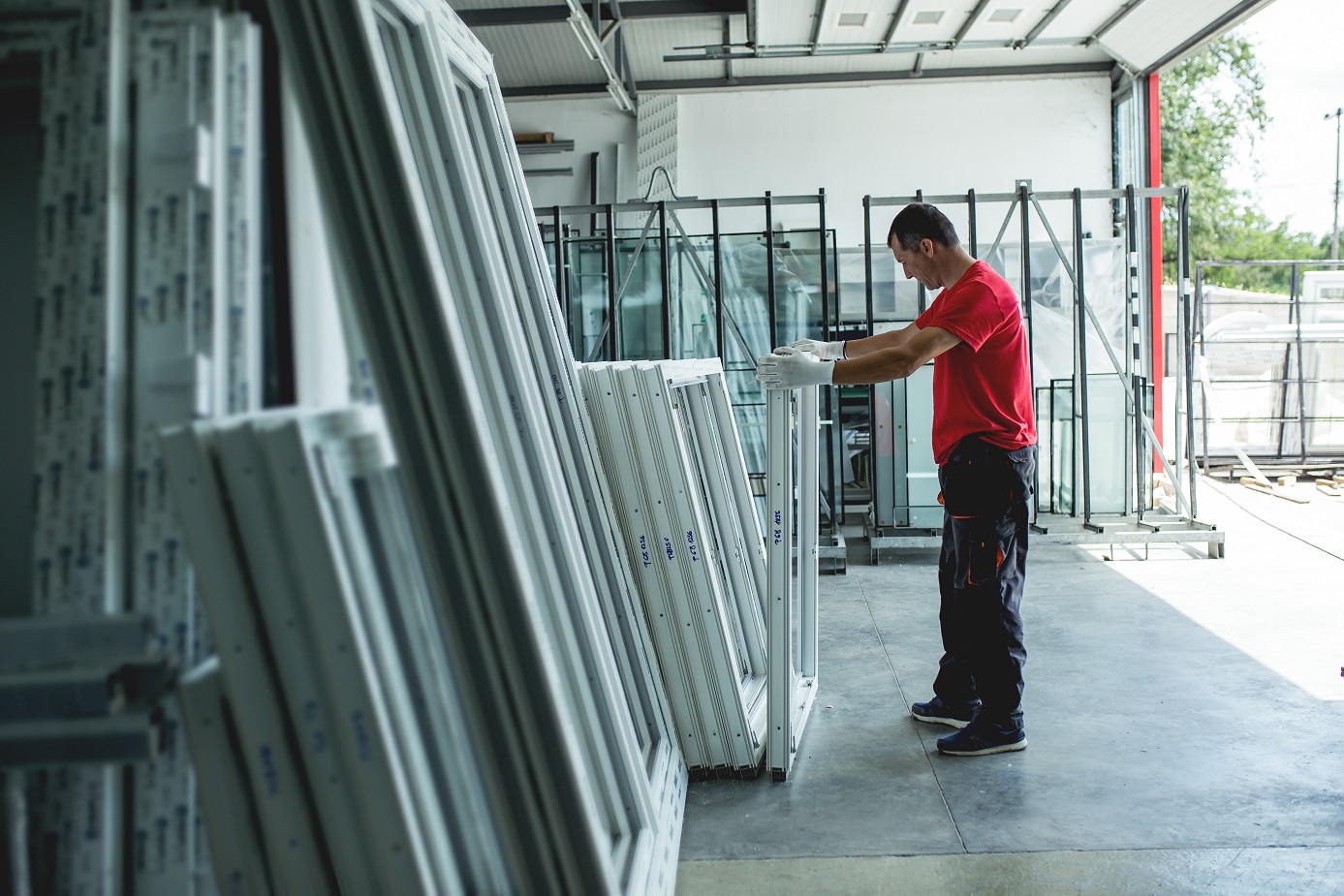 A man standing by a stack of windows in a warehouse