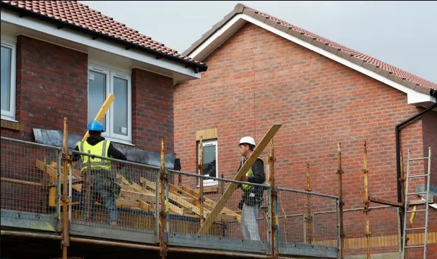 Two builders on scaffolding on a house
